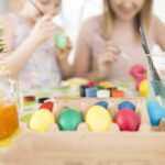 Children painting real eggs, placed in a biodegradable egg carton, as part of an eco-friendly Easter celebration.